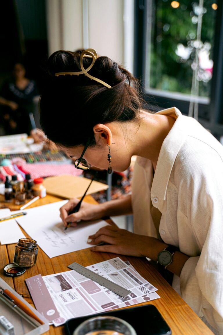 A woman focused on creating calligraphy art in a well-organized creative workspace.